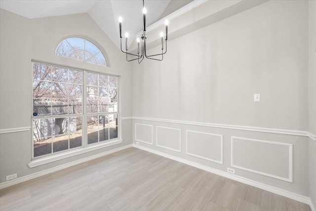 unfurnished dining area with a notable chandelier, wood finished floors, and vaulted ceiling