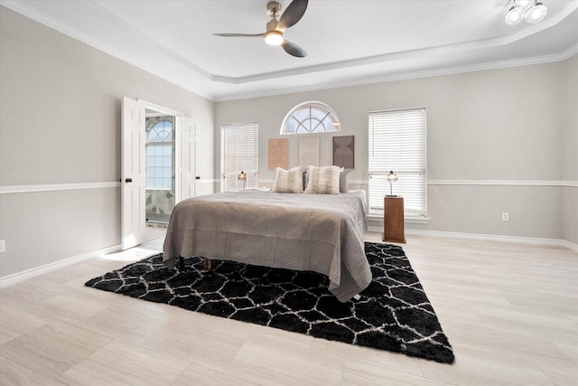 bedroom with a raised ceiling, ceiling fan, and ensuite bathroom