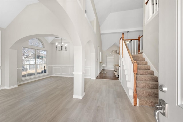 foyer featuring arched walkways, high vaulted ceiling, a chandelier, and stairway