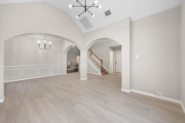 unfurnished living room featuring arched walkways, visible vents, high vaulted ceiling, and a notable chandelier