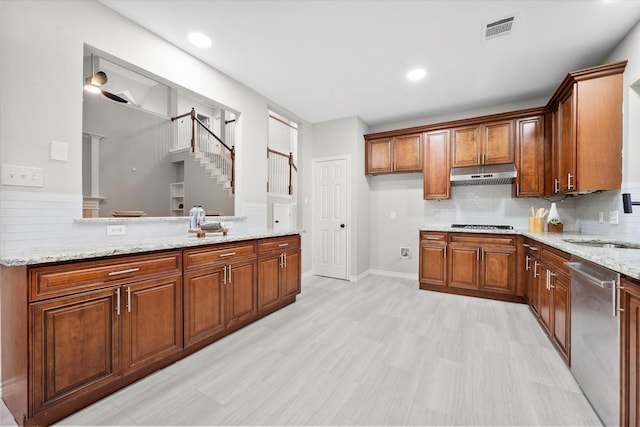 kitchen with tasteful backsplash, dishwasher, sink, gas stovetop, and light stone countertops