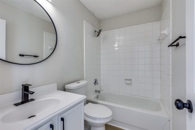 full bathroom featuring tiled shower / bath, vanity, toilet, and a textured ceiling