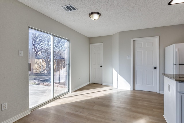 unfurnished dining area featuring light hardwood / wood-style floors and a textured ceiling