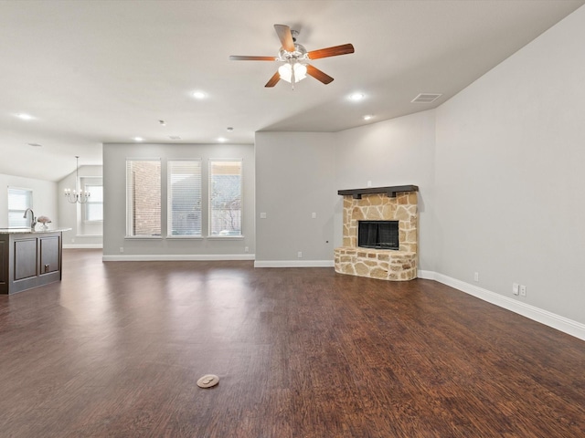 unfurnished living room with dark wood-style flooring, a fireplace, visible vents, baseboards, and ceiling fan with notable chandelier