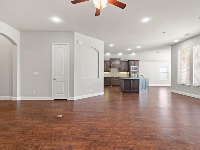 unfurnished living room featuring visible vents, arched walkways, dark wood-type flooring, and recessed lighting