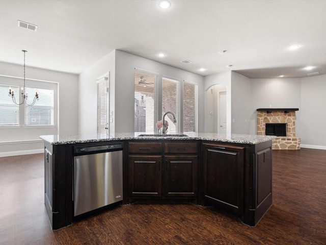 kitchen with a stone fireplace, a sink, visible vents, stainless steel dishwasher, and dark wood finished floors