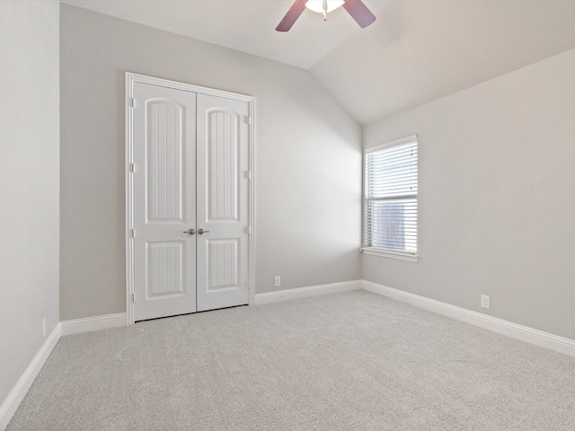 unfurnished bedroom featuring lofted ceiling, carpet, baseboards, and a closet