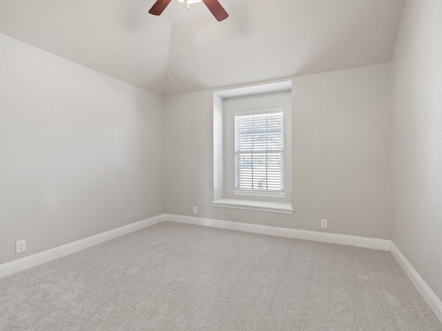 carpeted empty room with baseboards, vaulted ceiling, and a ceiling fan