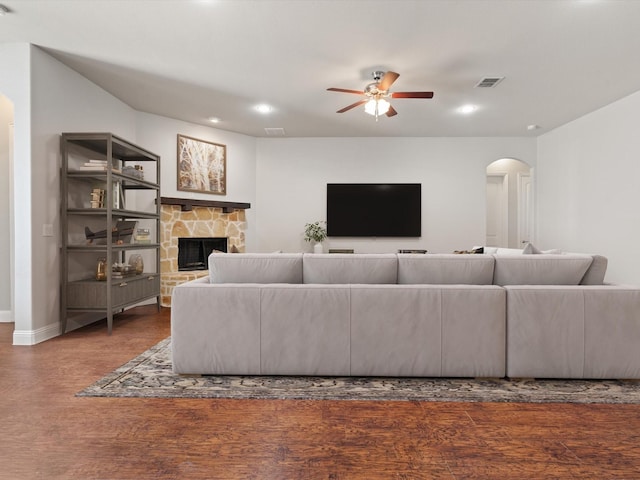 living area with arched walkways, a fireplace, wood finished floors, and visible vents