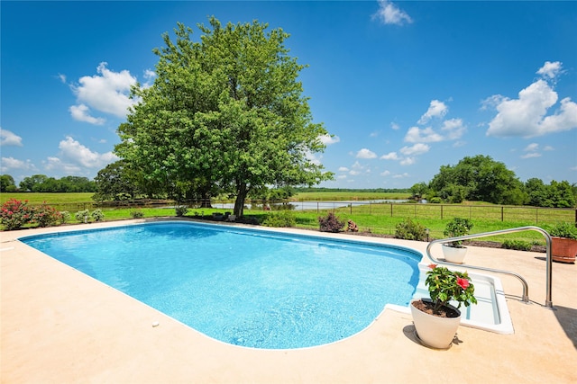 view of swimming pool with a patio area and a rural view