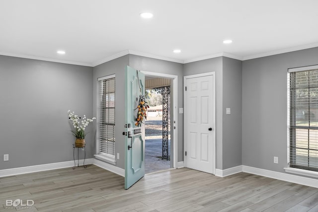 foyer entrance with light hardwood / wood-style flooring, crown molding, and a wealth of natural light