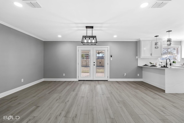 unfurnished living room featuring sink, crown molding, and light wood-type flooring