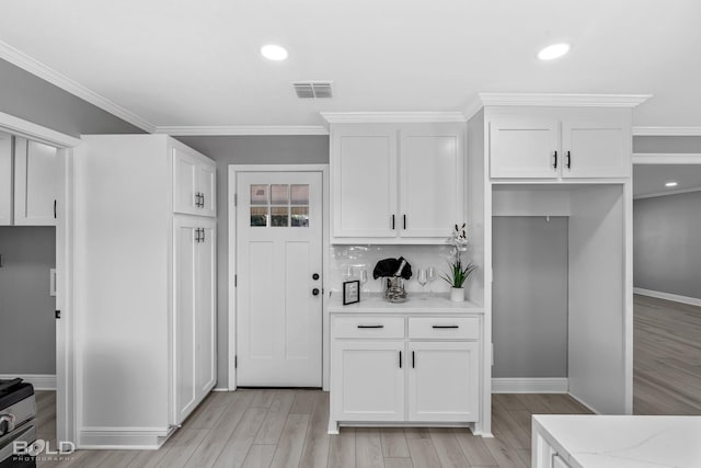 kitchen with light stone counters, crown molding, light hardwood / wood-style flooring, and white cabinets