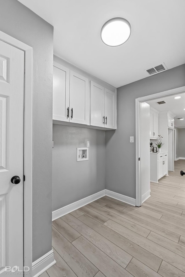 washroom with cabinets, washer hookup, and light hardwood / wood-style flooring