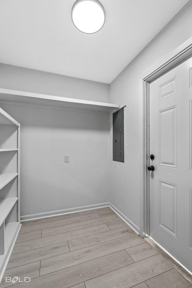 laundry room with electric panel and light wood-type flooring