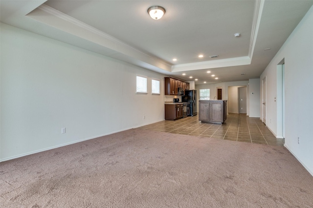 unfurnished living room featuring a raised ceiling, crown molding, and carpet flooring