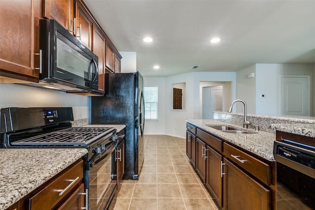 kitchen with light tile patterned floors, light stone countertops, sink, and black appliances