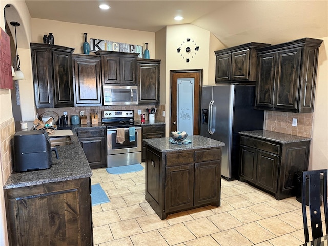 kitchen featuring light tile patterned floors, appliances with stainless steel finishes, dark brown cabinets, a center island, and decorative backsplash