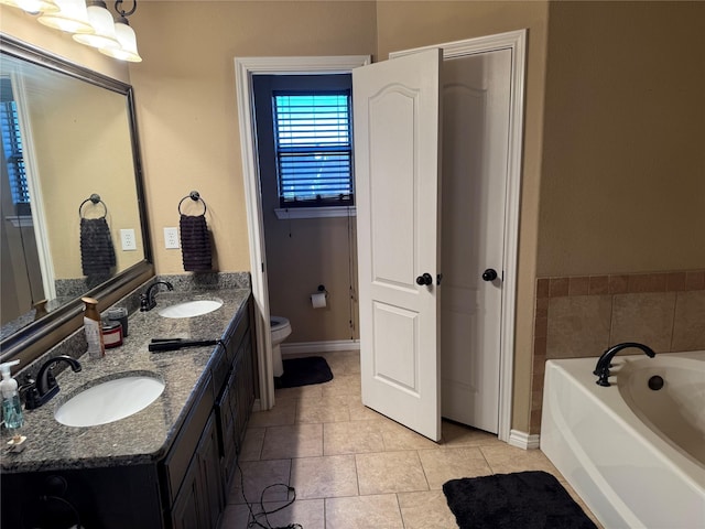 bathroom featuring vanity, a bathing tub, tile patterned floors, and toilet