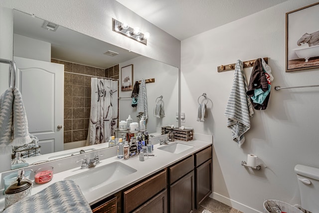 bathroom with double vanity, a sink, a shower with shower curtain, and toilet