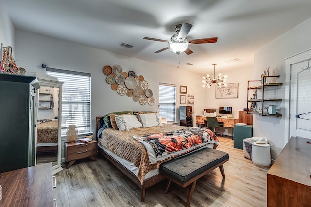 bedroom with visible vents, light wood-style flooring, and ceiling fan with notable chandelier