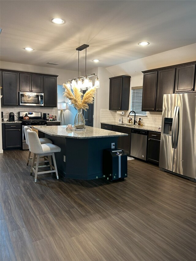 kitchen with appliances with stainless steel finishes, tasteful backsplash, a center island, and dark wood-style flooring