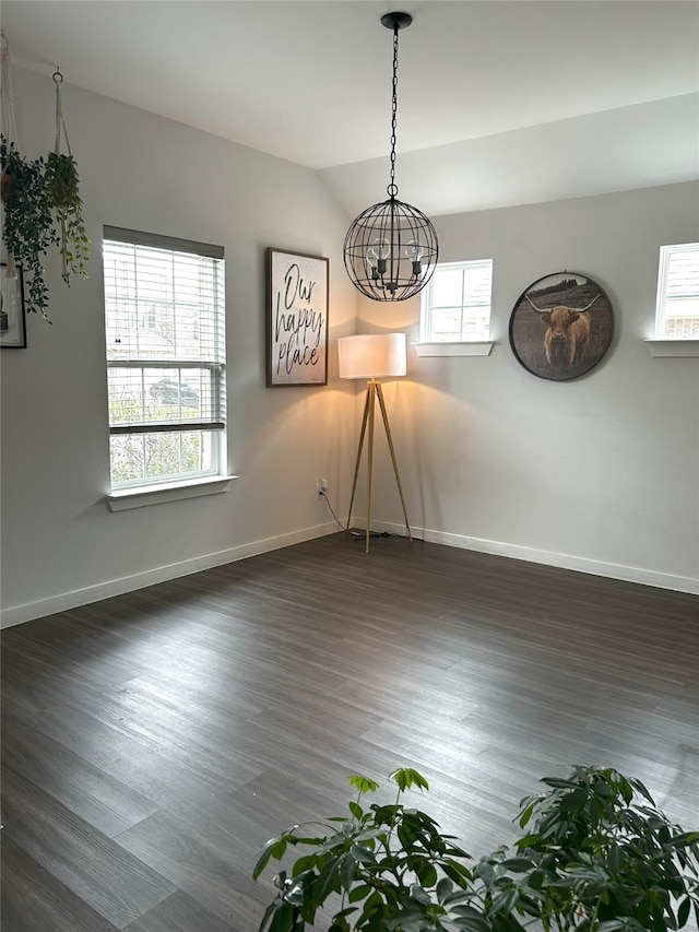 unfurnished dining area featuring an inviting chandelier, dark wood-style flooring, baseboards, and a healthy amount of sunlight
