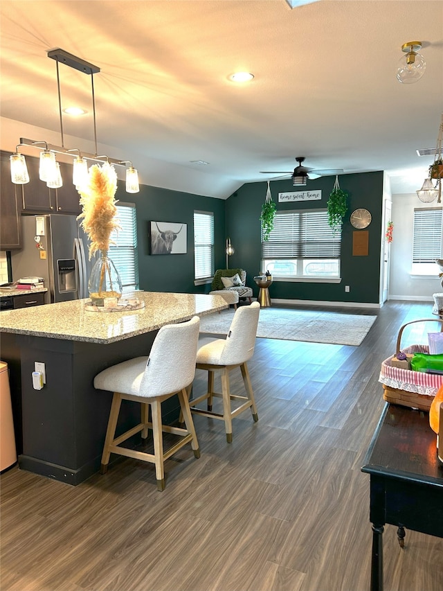 kitchen with ceiling fan, stainless steel refrigerator with ice dispenser, visible vents, light stone counters, and dark wood-style floors