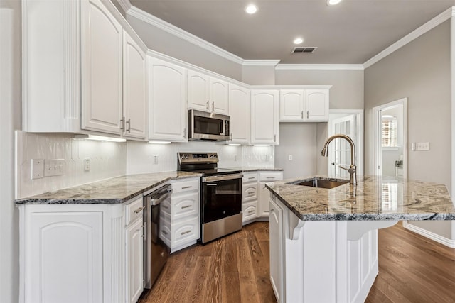 kitchen featuring stainless steel appliances, an island with sink, sink, and white cabinetry