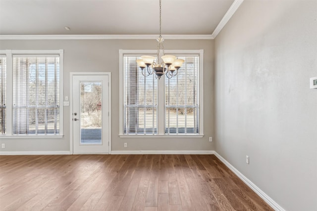 unfurnished dining area featuring ornamental molding, wood-type flooring, and a notable chandelier