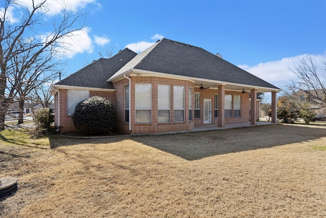 rear view of property with ceiling fan and a yard