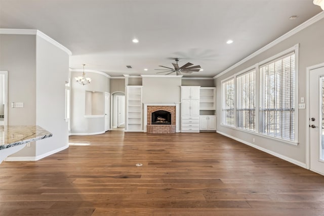 unfurnished living room featuring ornamental molding, a fireplace, dark hardwood / wood-style flooring, and ceiling fan with notable chandelier