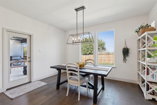 dining area with dark wood-type flooring and an inviting chandelier