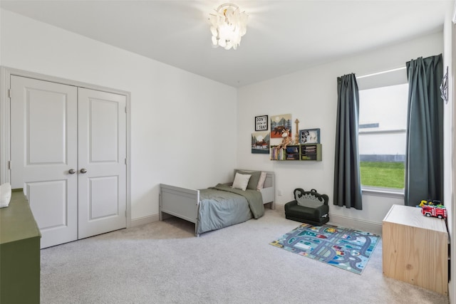 carpeted bedroom featuring a chandelier and a closet