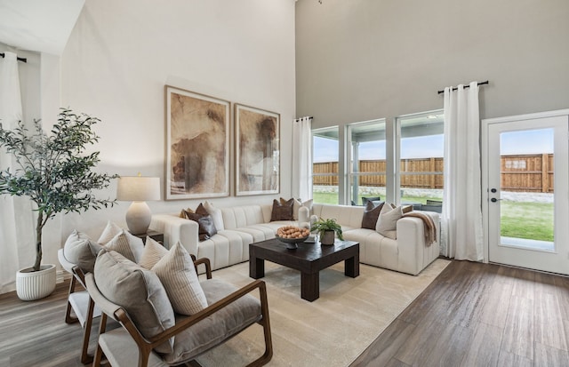 living room featuring plenty of natural light, a towering ceiling, and light hardwood / wood-style flooring