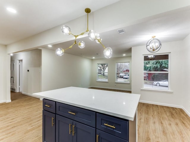 kitchen with decorative light fixtures, light hardwood / wood-style floors, a center island, and blue cabinetry