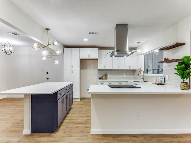 kitchen featuring pendant lighting, tasteful backsplash, sink, white cabinets, and island exhaust hood