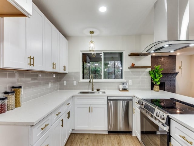 kitchen featuring appliances with stainless steel finishes, white cabinetry, backsplash, ventilation hood, and decorative light fixtures