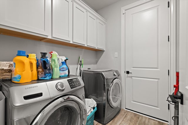 laundry room with cabinets, washer and dryer, and light wood-type flooring