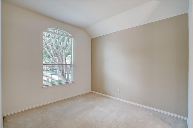 carpeted empty room featuring lofted ceiling