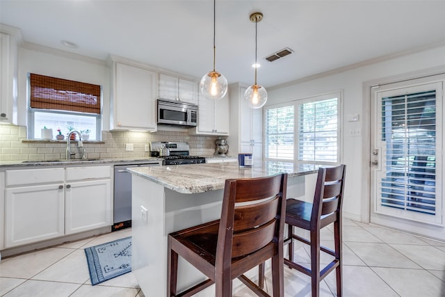 kitchen with sink, a breakfast bar, appliances with stainless steel finishes, hanging light fixtures, and a center island