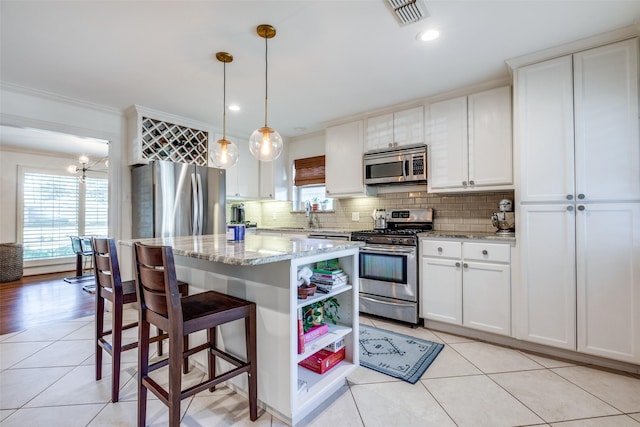 kitchen featuring hanging light fixtures, stainless steel appliances, and white cabinets