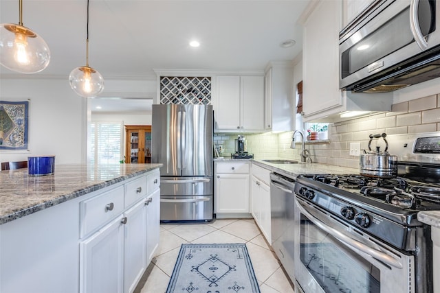 kitchen featuring sink, stainless steel appliances, light stone countertops, white cabinets, and decorative light fixtures