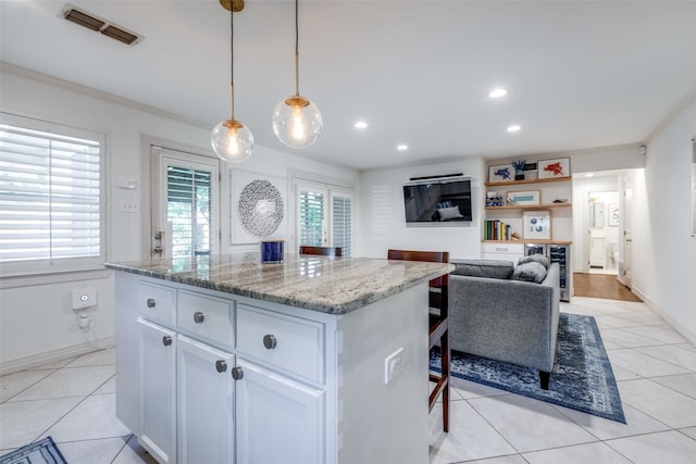 kitchen featuring pendant lighting, light tile patterned floors, light stone countertops, and white cabinets