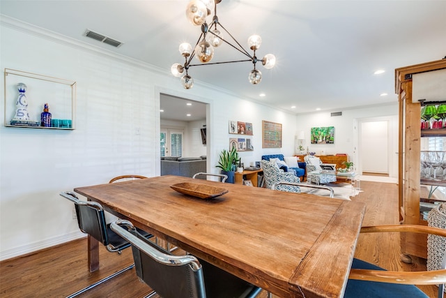 dining space with dark hardwood / wood-style flooring, ornamental molding, and an inviting chandelier