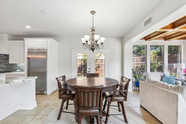 tiled dining space with coffered ceiling, a chandelier, beamed ceiling, and french doors