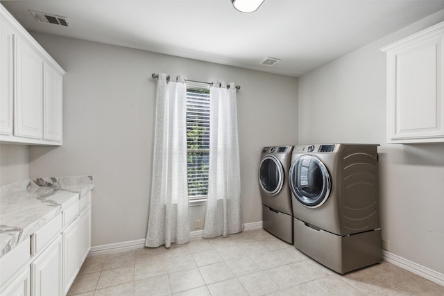 clothes washing area featuring cabinets, separate washer and dryer, and light tile patterned floors