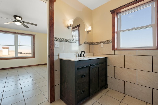 bathroom featuring a healthy amount of sunlight, tile patterned floors, tile walls, and vanity