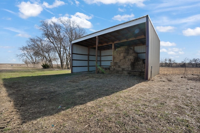 view of outbuilding featuring a rural view and a lawn