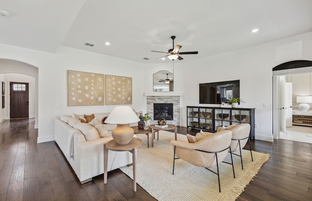 living room featuring dark wood-type flooring, ceiling fan, and a fireplace